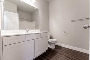 Bathroom with toilet, vanity, walk in shower, and wood-type flooring