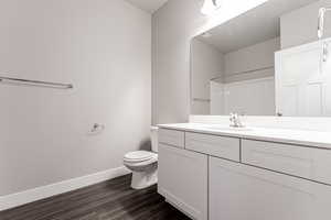 Bathroom with toilet, vanity, a shower, and wood-type flooring