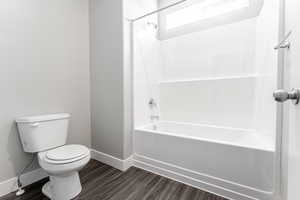 Bathroom with toilet, bathing tub / shower combination, and hardwood / wood-style floors