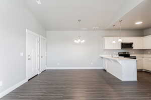 Kitchen featuring kitchen peninsula, white cabinets, and decorative light fixtures