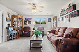 Carpeted living room featuring ceiling fan