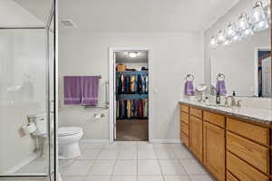 Bathroom featuring tile patterned flooring, toilet, vanity, and walk in shower