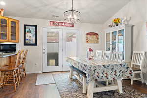 Dining space with hardwood / wood-style floors, vaulted ceiling, and a chandelier