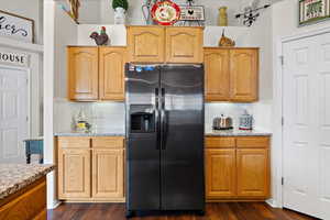 Kitchen with dark hardwood / wood-style flooring, decorative backsplash, and black fridge with ice dispenser