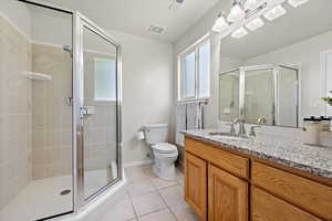 Bathroom with tile patterned floors, vanity, walk in shower, and toilet