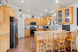 Kitchen featuring dark hardwood / wood-style floors, tasteful backsplash, electric range oven, kitchen peninsula, and refrigerator with ice dispenser