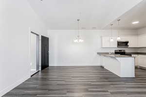 Kitchen featuring appliances with stainless steel finishes, hanging light fixtures, white cabinets, a breakfast bar, and kitchen peninsula