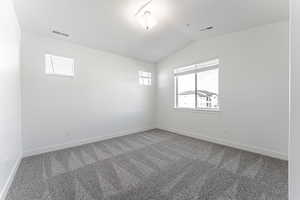 Carpeted empty room with lofted ceiling