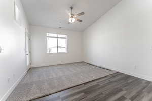 Empty room with hardwood / wood-style floors, lofted ceiling, and ceiling fan