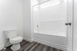 Bathroom with  shower combination, toilet, and hardwood / wood-style flooring