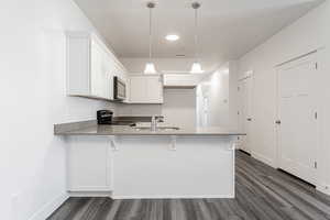 Kitchen with appliances with stainless steel finishes, pendant lighting, kitchen peninsula, white cabinets, and a breakfast bar area