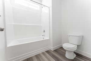 Bathroom featuring hardwood / wood-style floors, shower / bathtub combination, and toilet