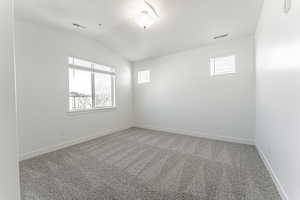 Spare room featuring vaulted ceiling and carpet flooring