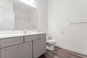 Bathroom with hardwood / wood-style floors, a shower, vanity, and toilet