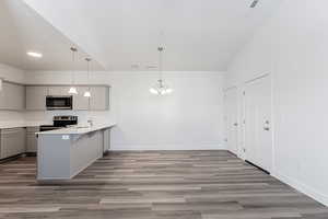 Kitchen with pendant lighting, stainless steel appliances, gray cabinetry, and kitchen peninsula