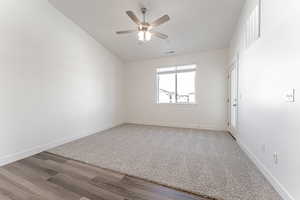 Empty room with lofted ceiling, ceiling fan, and wood-type flooring