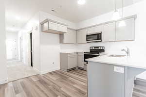 Kitchen featuring kitchen peninsula, a breakfast bar, decorative light fixtures, sink, and appliances with stainless steel finishes