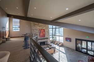 Interior space with beamed ceiling, carpet, a stone fireplace, and plenty of natural light