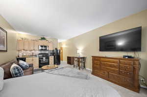 Bedroom featuring black fridge, light carpet, and sink