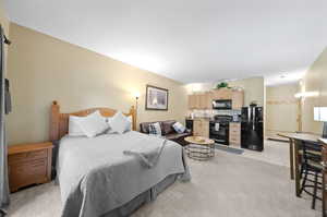 Bedroom with sink, light tile patterned flooring, and black refrigerator