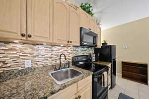 Kitchen featuring light brown cabinets, tasteful backsplash, light tile patterned floors, sink, and black appliances