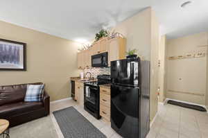 Kitchen with light tile patterned flooring, decorative backsplash, and black appliances