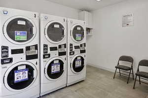 Washroom with washing machine and dryer, stacked washer / drying machine, and light tile patterned floors