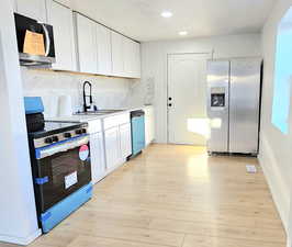 Kitchen with light hardwood / wood-style floors, stainless steel appliances, and white cabinetry