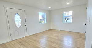 Entryway with a textured ceiling, light hardwood / wood-style flooring, and a healthy amount of sunlight