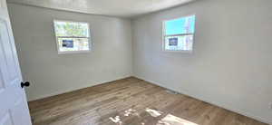 Spare room with light wood-type flooring and a textured ceiling