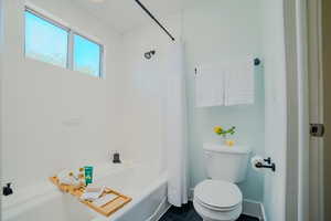 Bathroom featuring shower / bath combination with curtain, toilet, and tile patterned floors