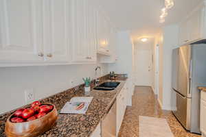 Kitchen with sink, stainless steel appliances, white cabinets, and dark stone counters