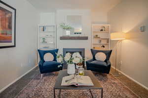 Living area with a fireplace and carpet flooring