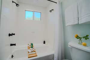 Bathroom with shower / bath combination with curtain and toilet