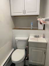 Bathroom featuring baseboard heating, vanity, and toilet