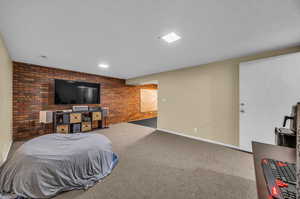 Bedroom featuring brick wall and carpet floors