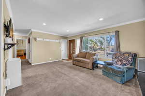 Living room with carpet floors and ornamental molding