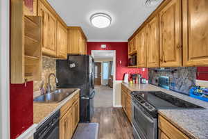 Kitchen with sink, ornamental molding, decorative backsplash, dark carpet, and black appliances