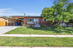 View of front facade with a front yard, carport, and apple tree.