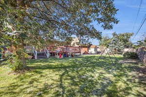 View of yard with a wooden deck, stone wall