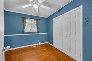 Unfurnished bedroom featuring a textured ceiling, a closet, ceiling fan, and wood-type flooring