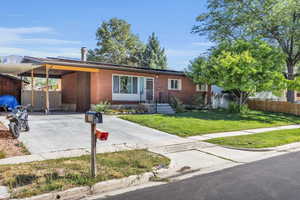 Ranch-style house featuring a carport and a front lawn