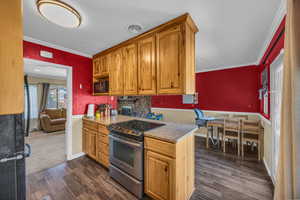 Kitchen featuring stainless steel electric range, backsplash, dark carpet, and ornamental molding