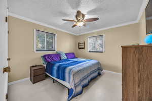 Bedroom featuring ceiling fan, a textured ceiling, built-in closet and ornamental molding