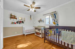 Bedroom featuring light wood-type flooring, a nursery area, and ornamental molding