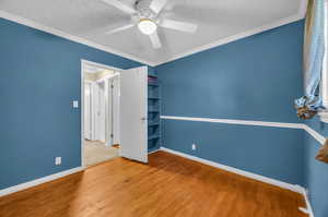 Unfurnished room featuring ceiling fan, a textured ceiling, crown molding, and wood-type flooring