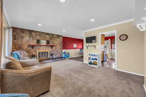 Living room featuring crown molding, dark hardwood / wood-style floors, and a stone fireplace