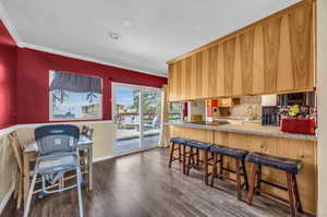 Kitchen with a kitchen breakfast bar, backsplash, ornamental molding, and dark hardwood / wood-style floors