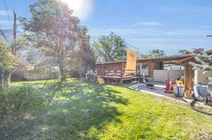 View of yard with a wooden deck and a patio