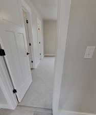 Corridor featuring light colored carpet
